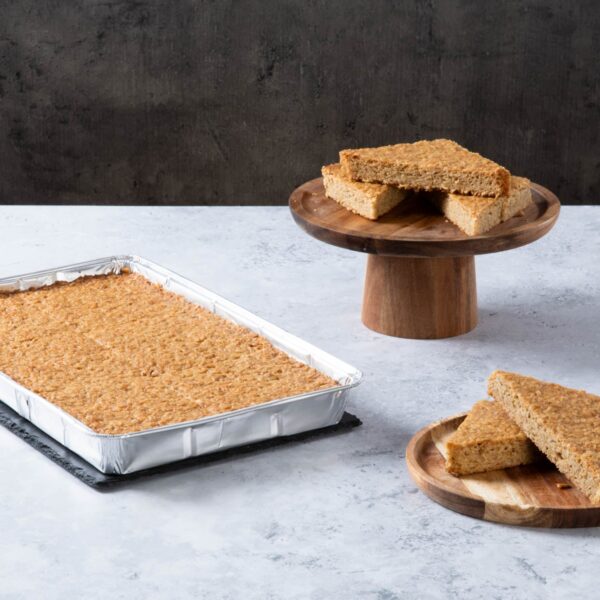 a golden traybake with sliced pieces on wooden plates