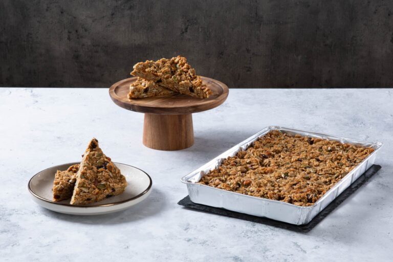 Chocolate cake with creamy frosting and chocolate topping on a wooden board.
